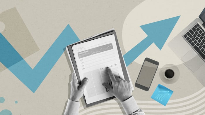 A hand points at a financial report with the background showing a graphic of an up-and-down arrow