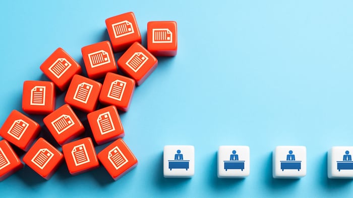 Files piling up alongside symbols of office workers