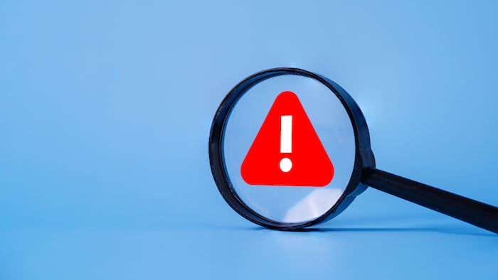 Magnifying glass with warning sign