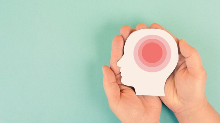 Representational image of a migraine headache attack with a paper cutout of a human head with red concentric circles running through the centre.