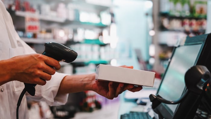 Pharmacist scanning medicine at till