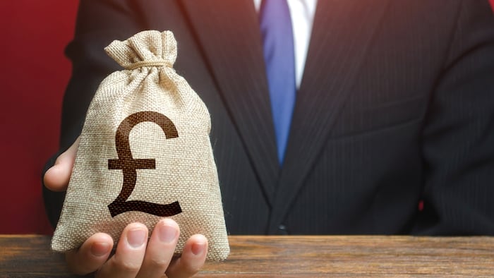 Man gives a British sterling money bag.