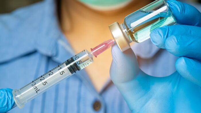 close up of medical worker holding syringe and vaccine bottle