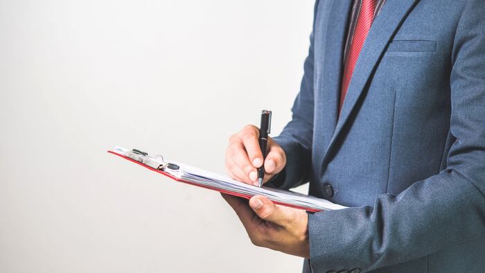 Man in suit looks at clipboard