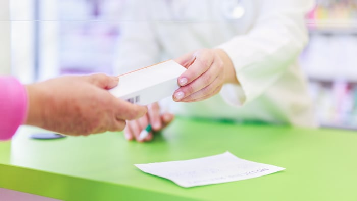 Pharmacist handing medicine to customer