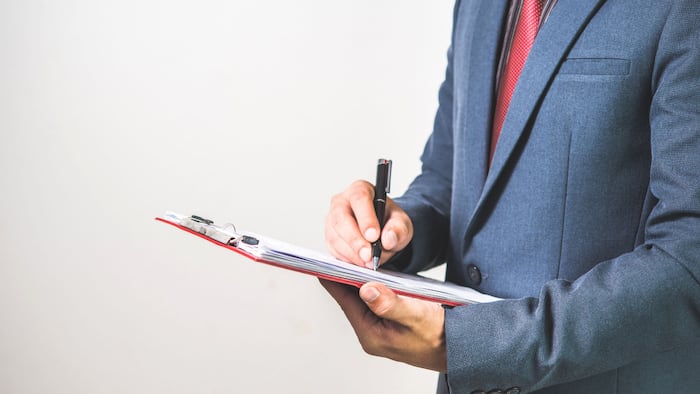 Man in suit looks at clipboard