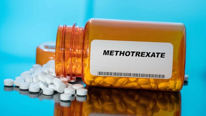 An orange tub with white pills inside it on its side, with some out of the top, and it labelled methotrexate